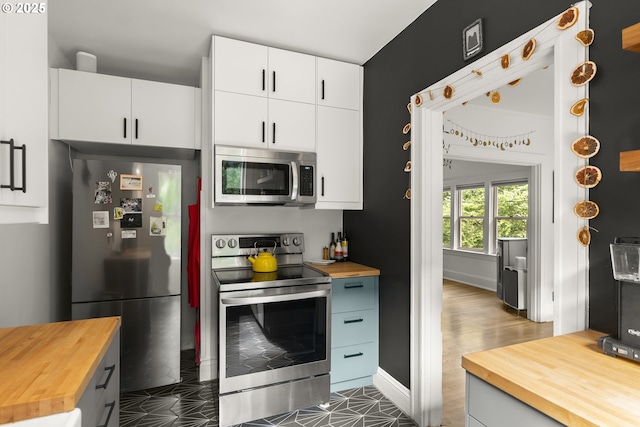 1529 SE Hawthorne Blvd Unit 204, Portland, OR 97214 - kitchen featuring wooden counters, baseboards, appliances with stainless steel finishes, and white cabinetry