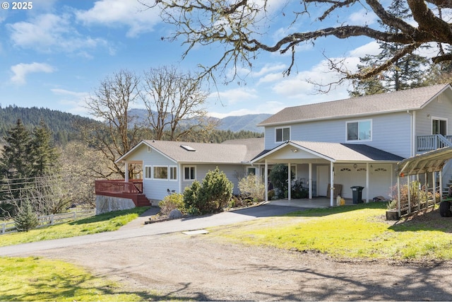 view of front of house featuring a front yard, fence, driveway, roof with shingles, and a mountain view