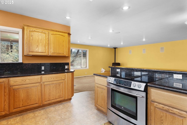 kitchen with baseboards, recessed lighting, stainless steel electric range oven, and dark stone counters