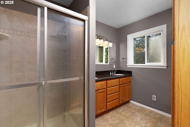 bathroom featuring a sink, baseboards, a stall shower, and double vanity