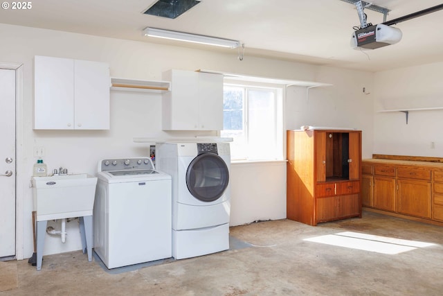 laundry room with a sink, a garage, cabinet space, and washing machine and dryer