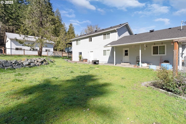 rear view of house with a yard, a patio area, a shingled roof, and fence