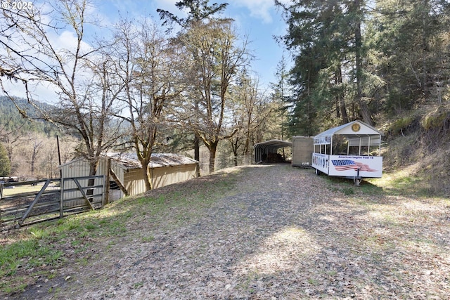 view of yard with a detached carport, driveway, and fence