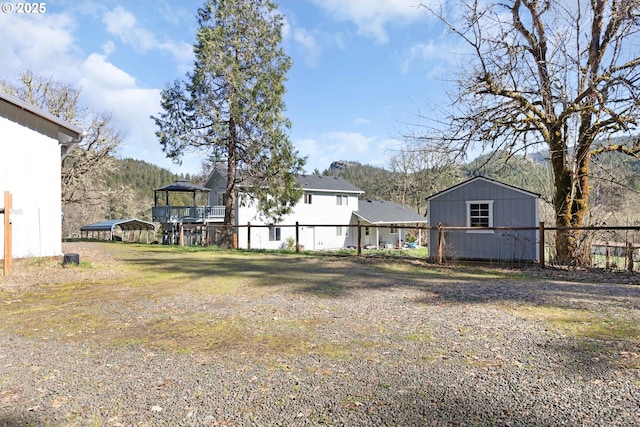 view of yard featuring an outdoor structure, a storage unit, and fence