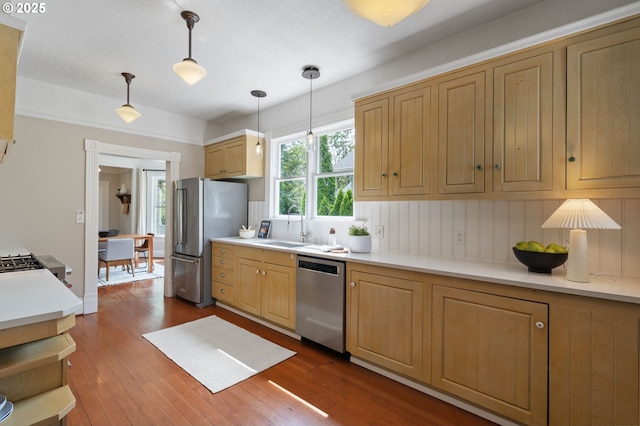 1905 N Sumner St, Portland, OR 97217 - kitchen with appliances with stainless steel finishes, dark wood-style floors, hanging light fixtures, light countertops, and light brown cabinetry
