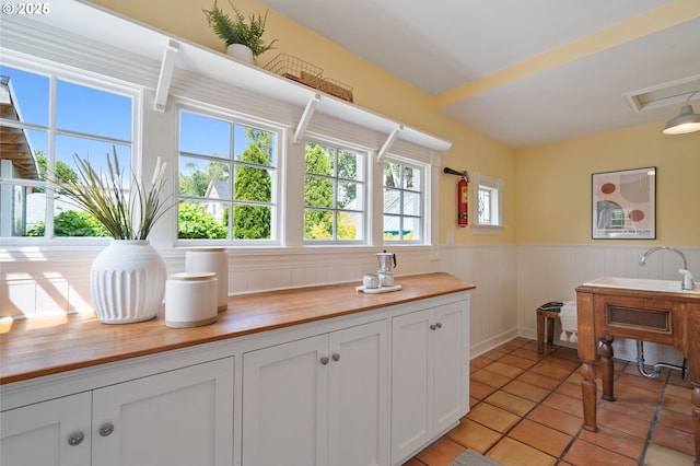 1905 N Sumner St, Portland, OR 97217 - kitchen featuring butcher block counters, a wainscoted wall, white cabinets, and light tile patterned floors