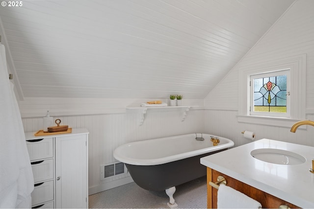 1905 N Sumner St, Portland, OR 97217 - bathroom featuring vaulted ceiling, a freestanding bath, vanity, wooden walls, and tile patterned floors