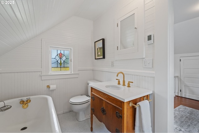 1905 N Sumner St, Portland, OR 97217 - bathroom with a freestanding bath, vaulted ceiling, vanity, wood walls, and a wainscoted wall