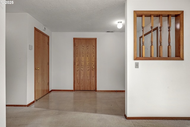 spare room featuring visible vents, a textured ceiling, and baseboards