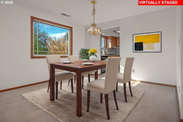 dining area with light carpet, visible vents, a chandelier, and baseboards