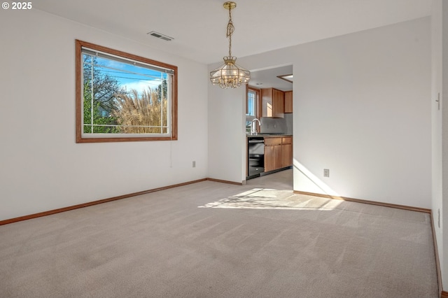 spare room featuring baseboards, visible vents, a chandelier, and light carpet