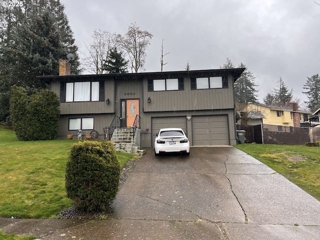 raised ranch featuring a front yard, an attached garage, and driveway