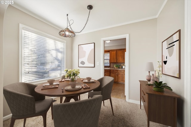 carpeted dining room with ornamental molding