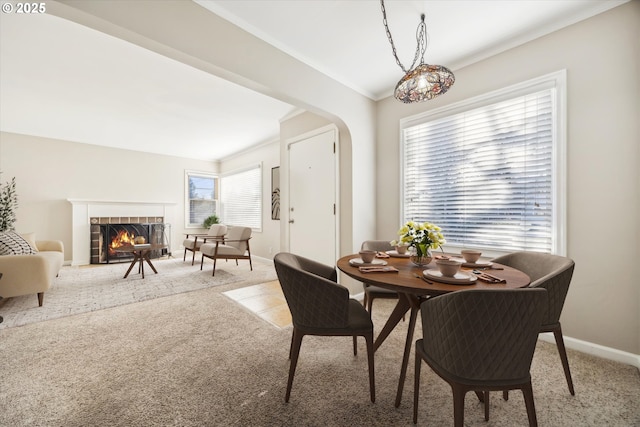 dining room with a tile fireplace, ornamental molding, and carpet flooring