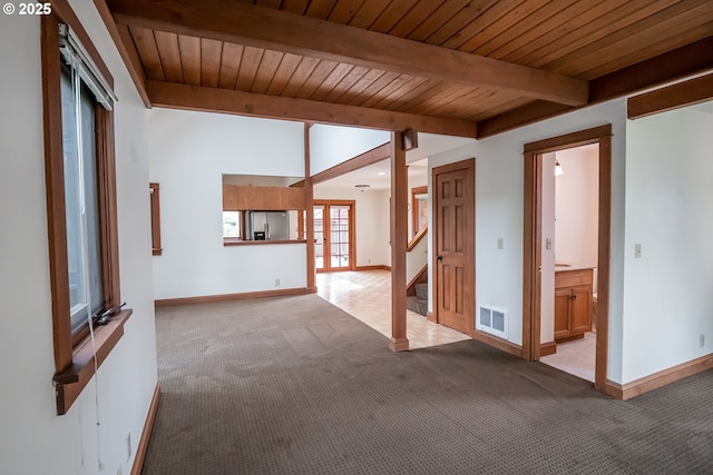 spare room featuring beamed ceiling, light carpet, and wood ceiling