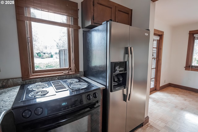 kitchen with light parquet floors, stainless steel fridge, and black / electric stove