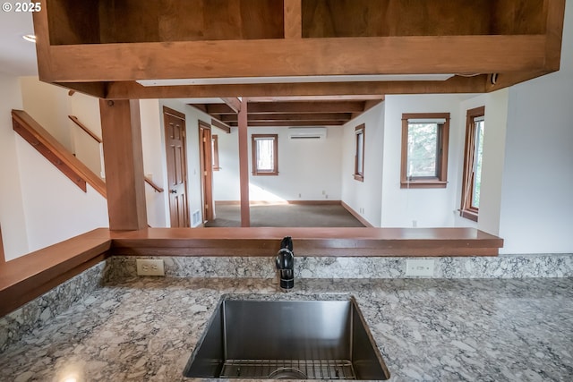 kitchen featuring an AC wall unit, sink, and beamed ceiling