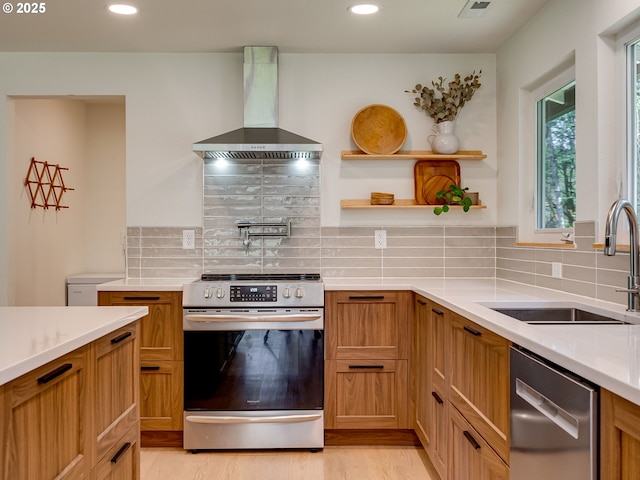 kitchen featuring a sink, light countertops, stainless steel appliances, and wall chimney exhaust hood