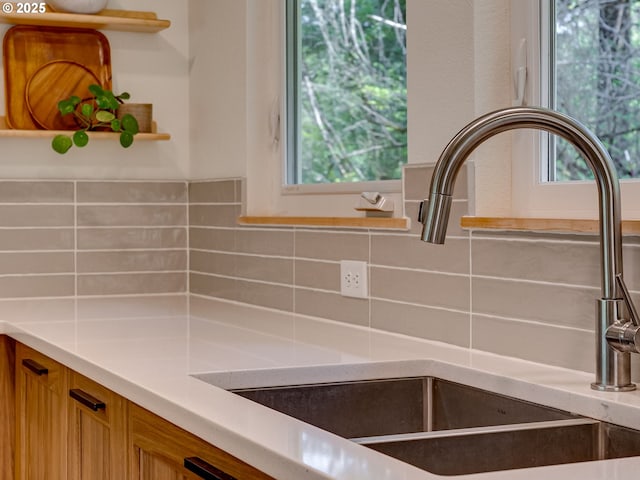 interior details with a sink, decorative backsplash, brown cabinets, and light countertops