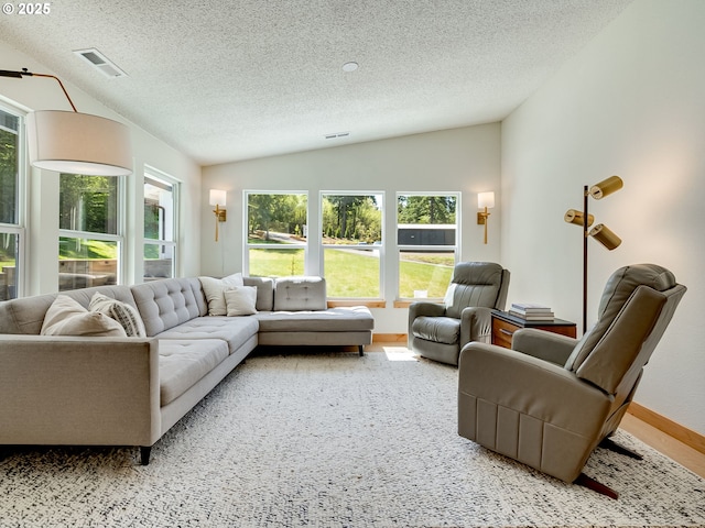 living room with a textured ceiling, visible vents, a wealth of natural light, and vaulted ceiling