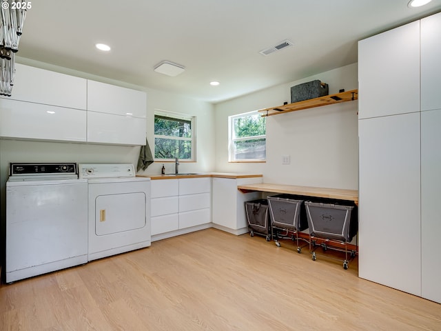 clothes washing area featuring visible vents, washing machine and dryer, cabinet space, recessed lighting, and light wood-style flooring