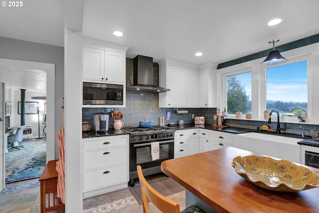 kitchen with stainless steel appliances, wall chimney range hood, dark countertops, and tasteful backsplash