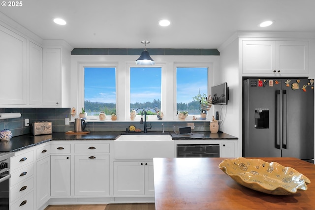 kitchen with dark countertops, white cabinetry, high quality fridge, and a sink