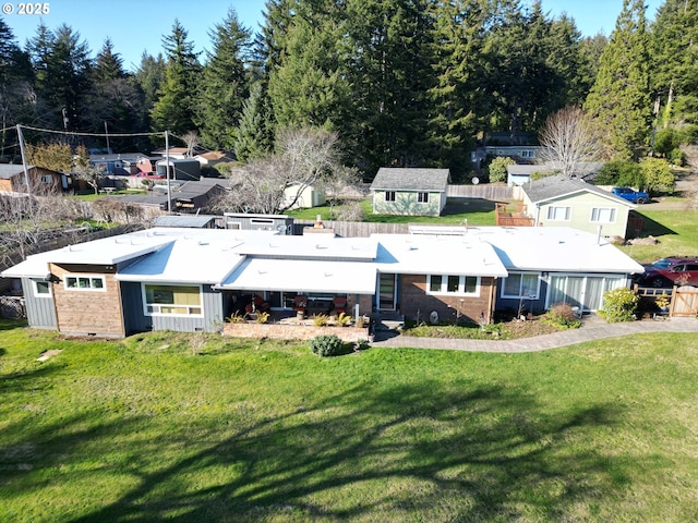 rear view of property featuring an outbuilding, a yard, and brick siding