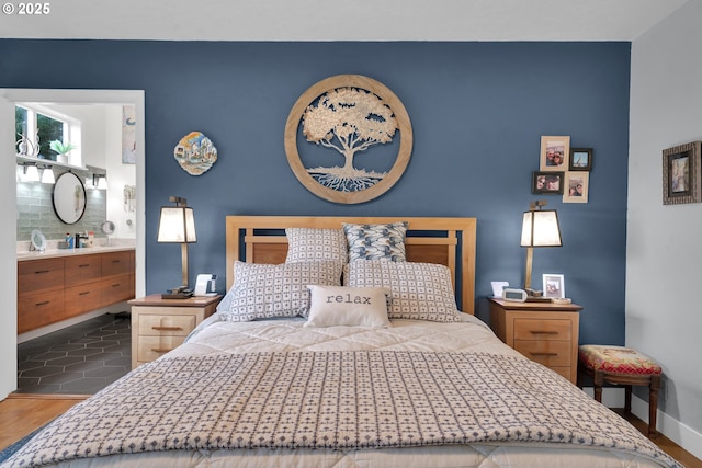 bedroom featuring wood finished floors, baseboards, and ensuite bathroom