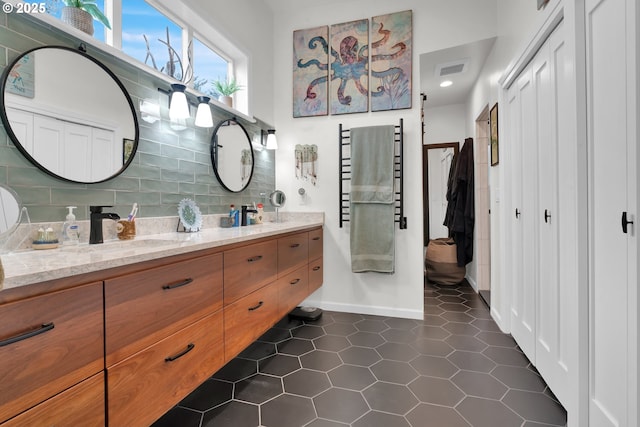 bathroom featuring double vanity, visible vents, decorative backsplash, tile patterned floors, and a sink