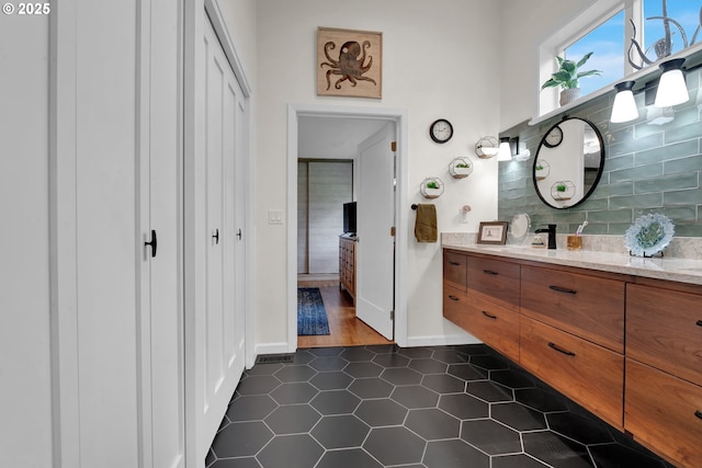 bathroom featuring baseboards, tasteful backsplash, vanity, and tile patterned floors