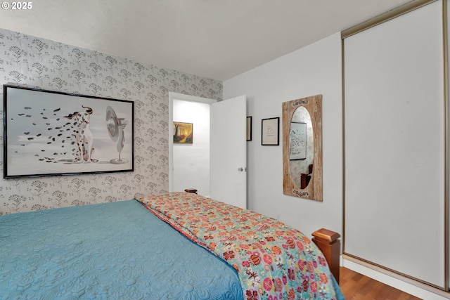 bedroom with wood finished floors and wallpapered walls