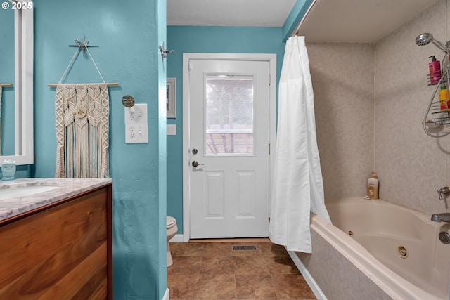 full bath featuring baseboards, visible vents, toilet, a combined bath / shower with jetted tub, and vanity