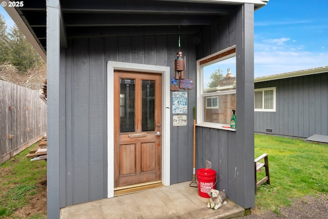 property entrance featuring crawl space, fence, and a lawn