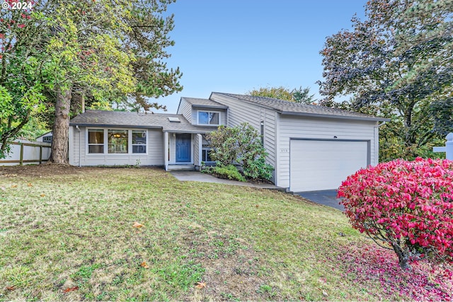 view of front of property with an attached garage, a front yard, aphalt driveway, and fence