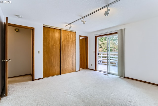 unfurnished bedroom with light carpet, access to exterior, visible vents, a closet, and rail lighting