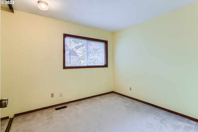spare room featuring carpet floors, visible vents, and baseboards
