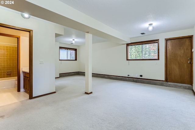 basement with visible vents, light carpet, and baseboards