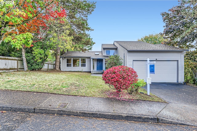view of front facade featuring an attached garage, driveway, fence, and a front yard