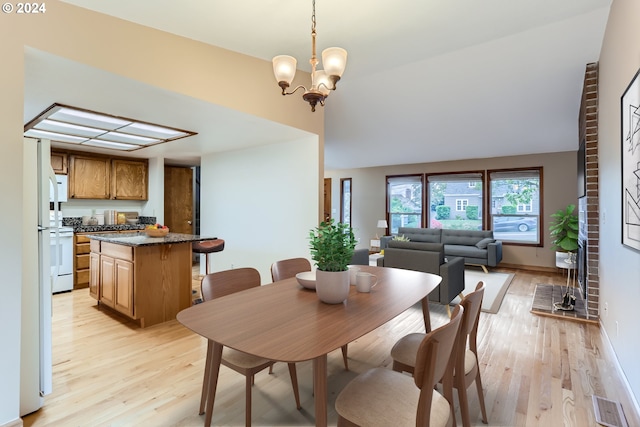 dining room with a chandelier, light wood-style floors, and lofted ceiling