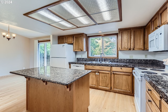 kitchen with a sink, brown cabinetry, white appliances, light wood-type flooring, and a kitchen bar