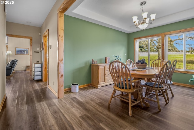 dining space featuring dark hardwood / wood-style flooring, a raised ceiling, and a chandelier