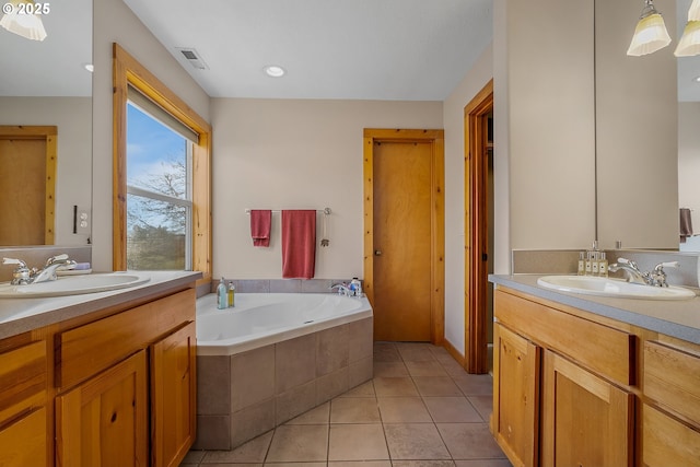 bathroom with a relaxing tiled tub, tile patterned floors, and vanity