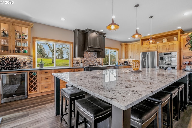 kitchen featuring appliances with stainless steel finishes, a large island, beverage cooler, and a kitchen breakfast bar