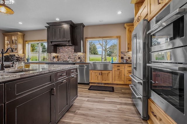 kitchen with sink, decorative backsplash, light wood-type flooring, and appliances with stainless steel finishes