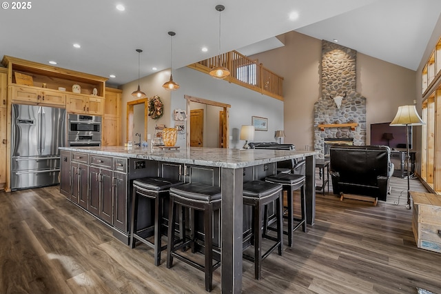 kitchen featuring a breakfast bar, dark brown cabinets, pendant lighting, stainless steel appliances, and a large island