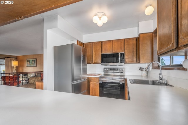 kitchen with sink, appliances with stainless steel finishes, kitchen peninsula, and a healthy amount of sunlight