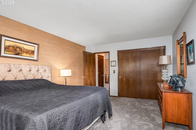 bedroom featuring a textured ceiling, wood walls, carpet flooring, and a closet