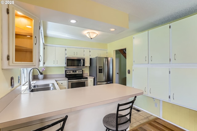 173 NE 32nd Ave, Hillsboro, OR 97124 - kitchen with appliances with stainless steel finishes, a sink, a peninsula, light countertops, and a breakfast bar area