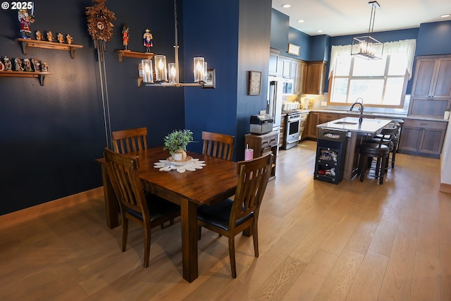 dining space with light wood-style flooring, baseboards, and a notable chandelier